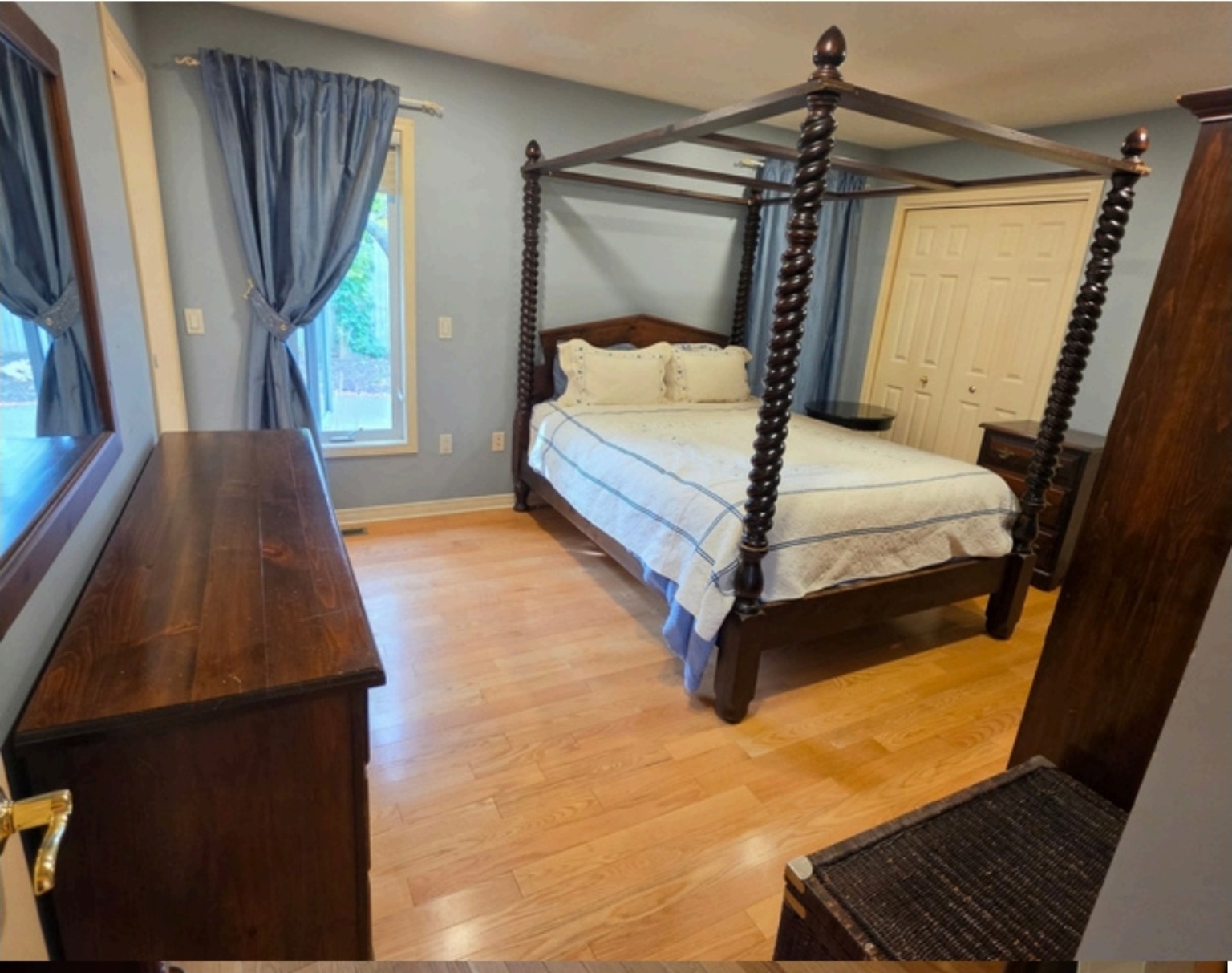 Before: primary bedroom with dark four-poster bed and blue walls